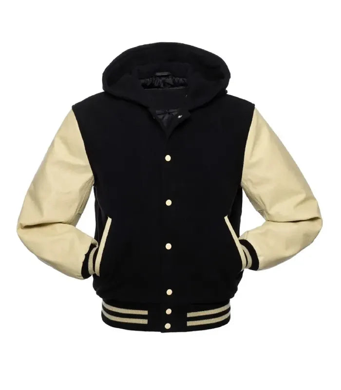 Front view of a black hooded varsity jacket featuring cream contrast leather sleeves, both hands in pockets, cream snap closures, and hood.