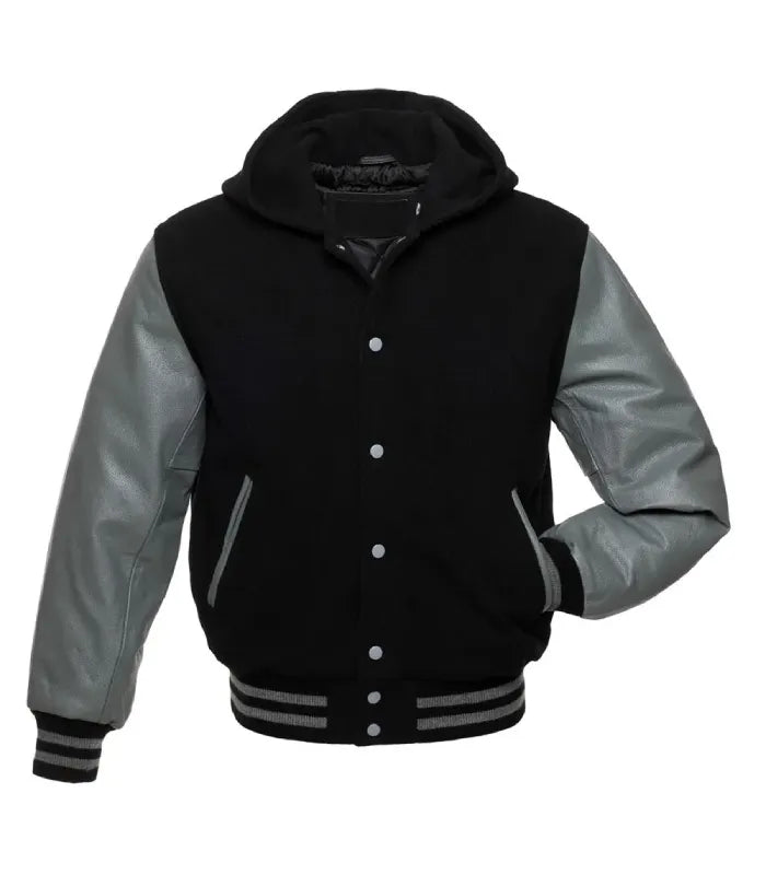 Front pose view of a black wool hooded varsity jacket with grey leather sleeves, silver snap buttons, and one hand inserted in the side pocket.