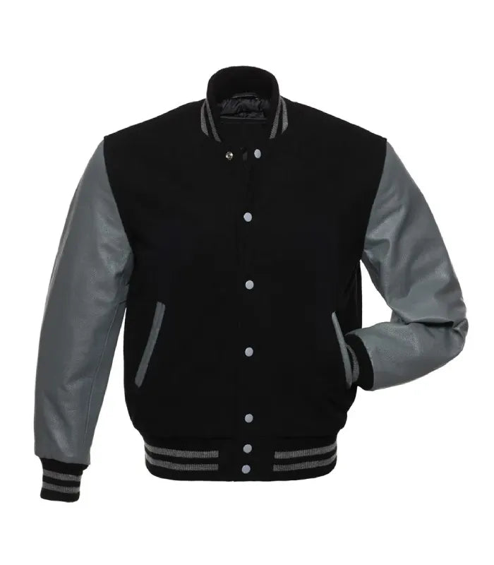 Front pose view of a black wool varsity jacket with grey leather sleeves, silver snap buttons, and one hand inserted in the side pocket.