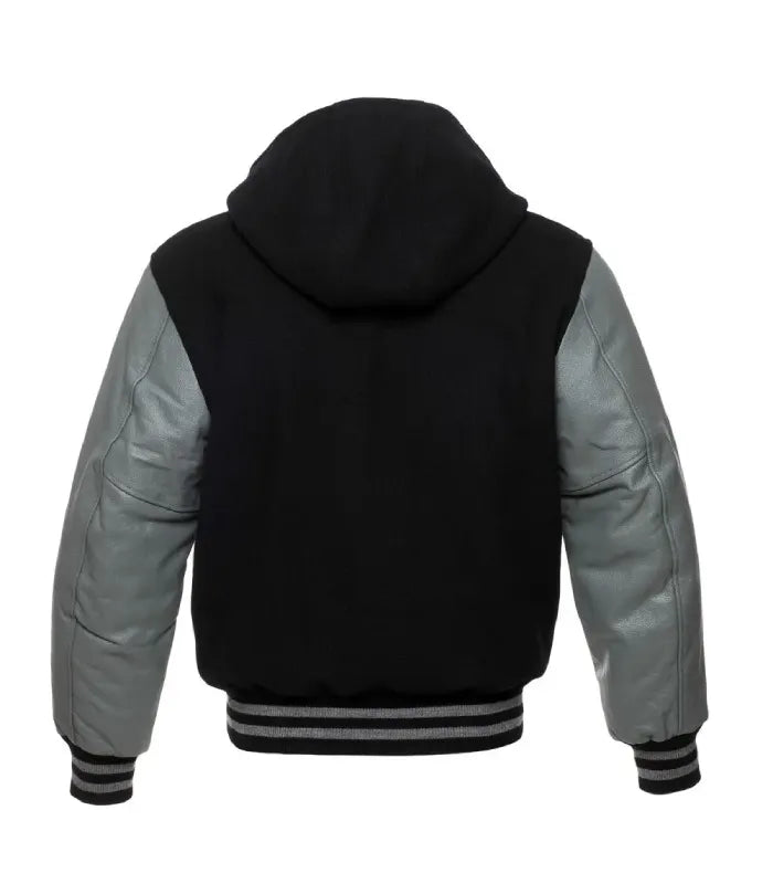 Rear view of a black and grey hooded varsity jacket with grey leather sleeves, full wool hood, plain black body, and grey-striped rib-knit hem.
