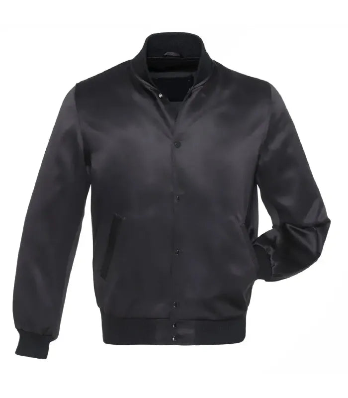 Front view of a solid black satin varsity jacket with matching black snap buttons, solid rib-knit collar and cuffs, and one hand in pocket.